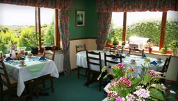 Cheerful breakfast room with sunny sea views at Rush Lake House